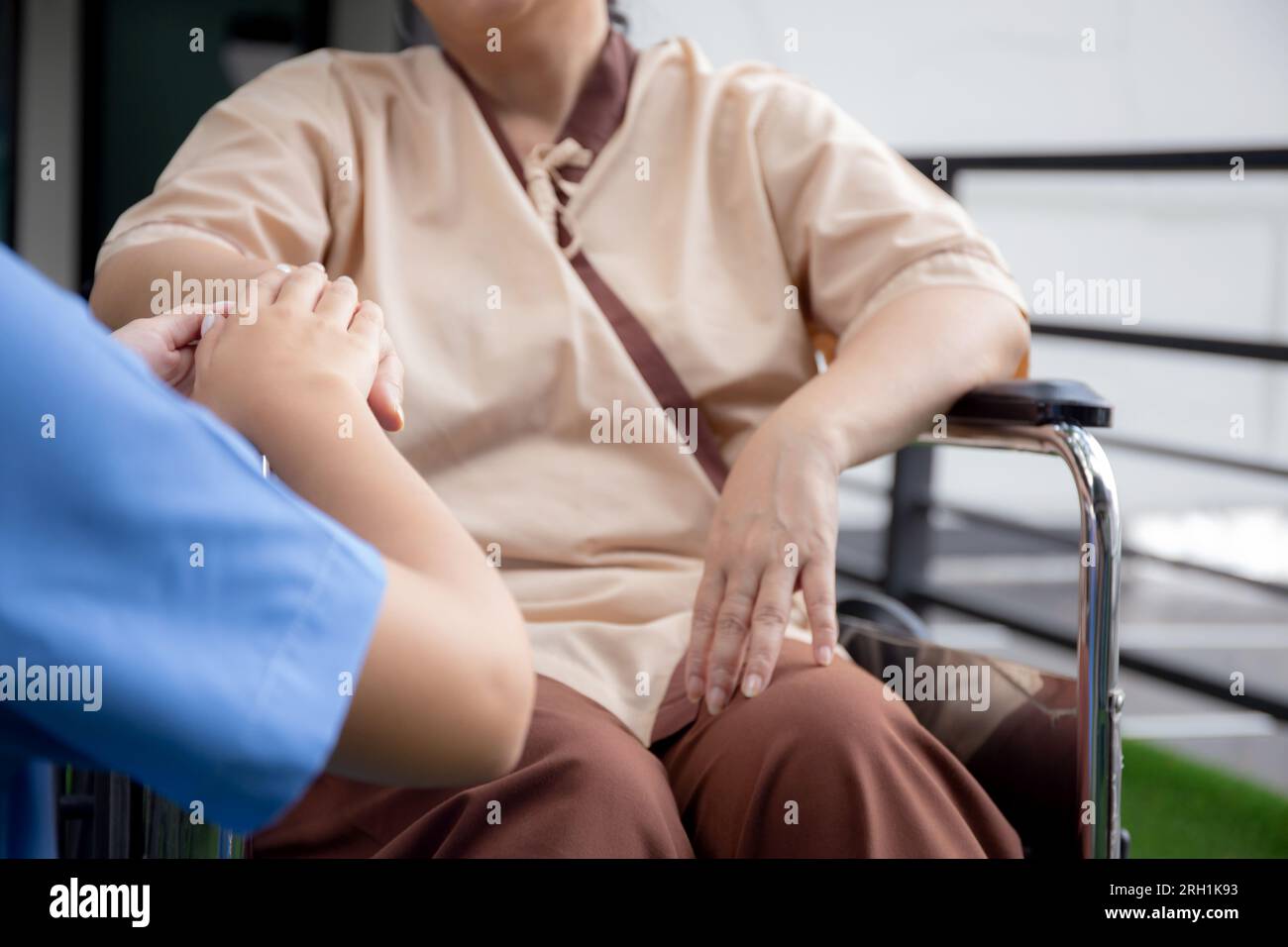 Closeup mani caregiver donna asiatica cura anziani seduti su sedia a rotelle, consoling per incoraggiare in giardino in ospedale, terapia senior e rehabilitati Foto Stock