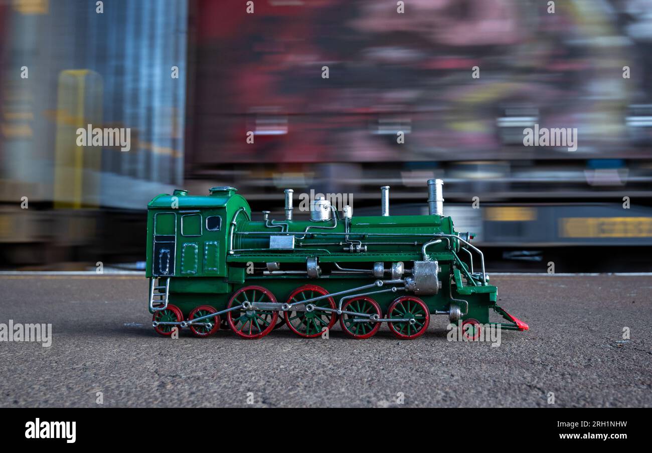 Modello di locomotiva a vapore verde con ruote rosse con movimento del treno sullo sfondo. Foto Stock