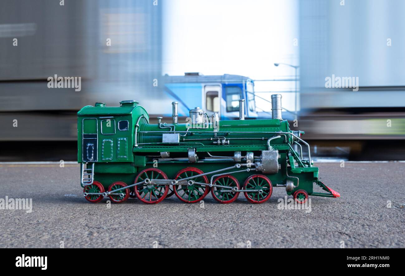 Modello di locomotiva a vapore verde con ruote rosse con movimento del treno sullo sfondo. Foto Stock