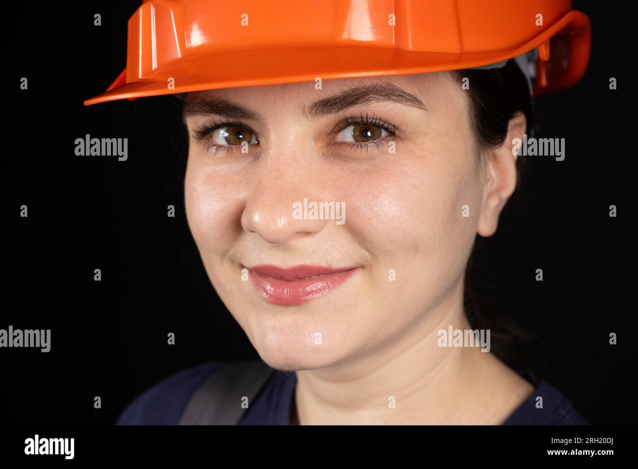 Una lavoratrice edile o un ingegnere che indossa una maschera arancione protettiva su sfondo nero Foto Stock