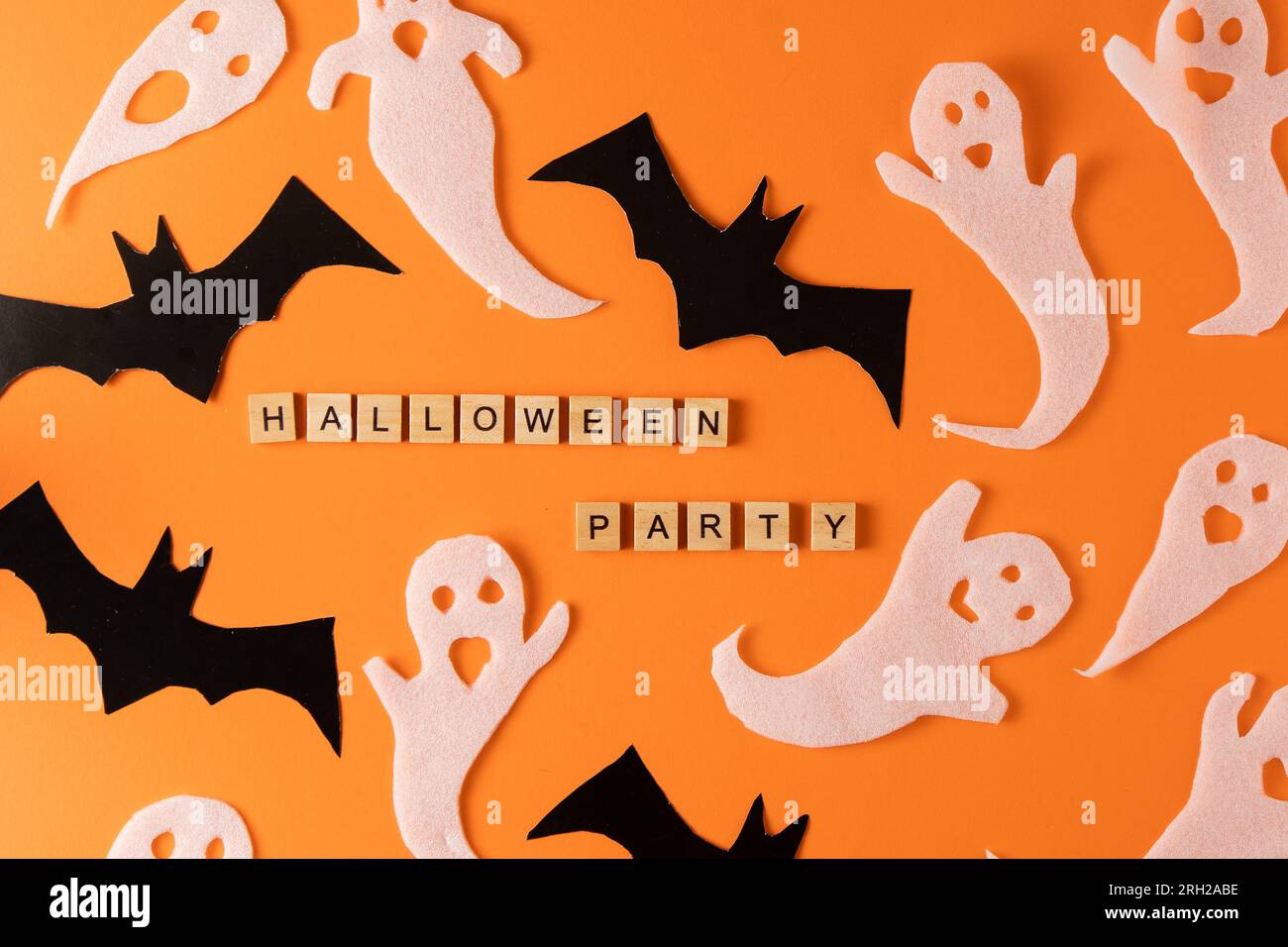 Fantasmi bianchi e mazza per la festa di Halloween. Immagine fantasma della carta di avvolgimento su sfondo arancione vista dall'alto. Fumetto Creepy Whisper. Fai-da-te fatto a mano. Impostare i caratteri boo. Parola frase di legno della lettera. Foto Stock