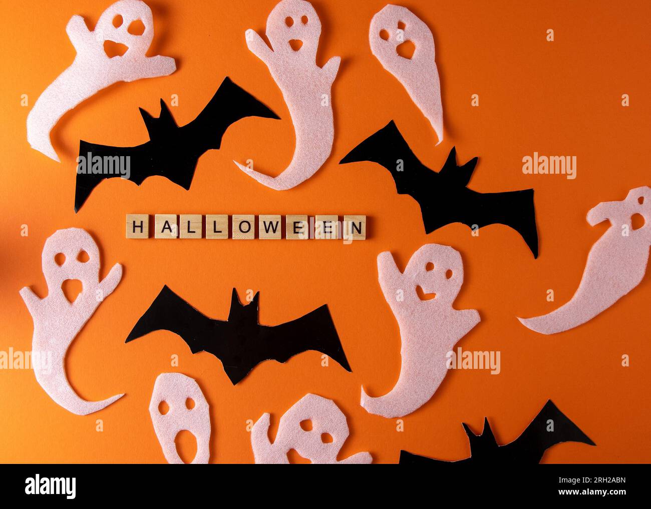 Fantasmi bianchi e mazza per la festa di Halloween. Immagine fantasma della carta di avvolgimento su sfondo arancione vista dall'alto. Fumetto Creepy Whisper. Fai-da-te fatto a mano. Impostare i caratteri boo. Parola frase di legno della lettera. Foto Stock