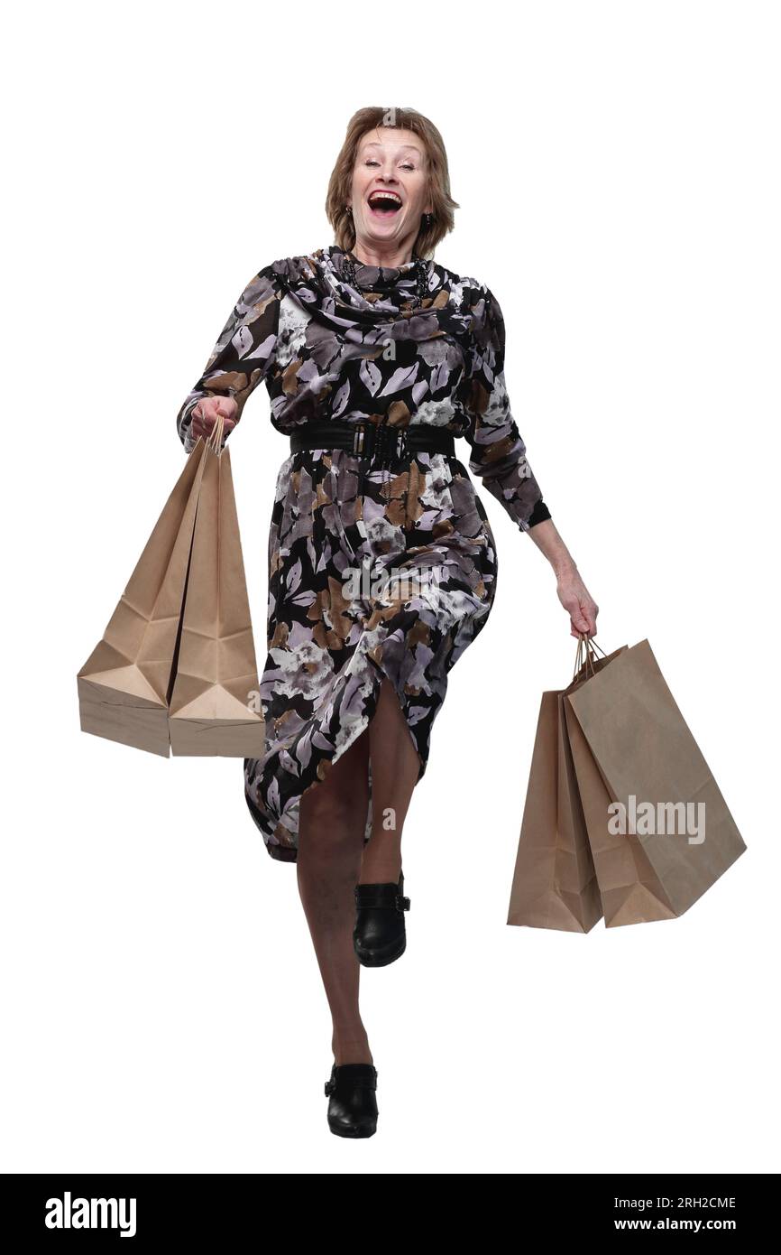 Donna anziana caucasica che cammina con le borse della spesa sorridendo allo spettatore. Concetto di shopping di successo Foto Stock