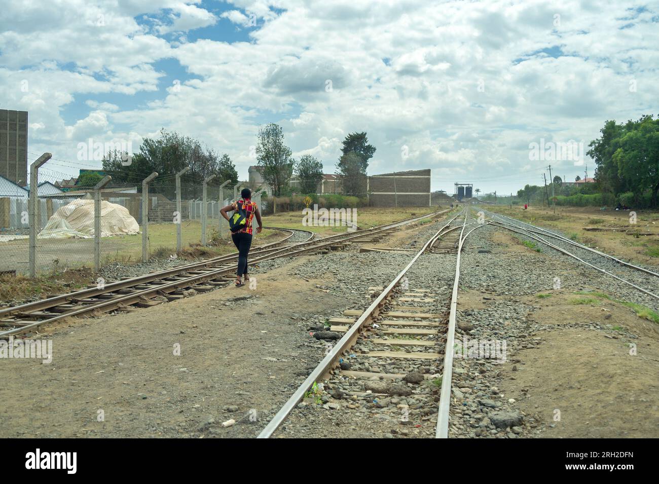 Una donna keniota cammina lungo i binari ferroviari, Nakuru, Kenya Foto Stock