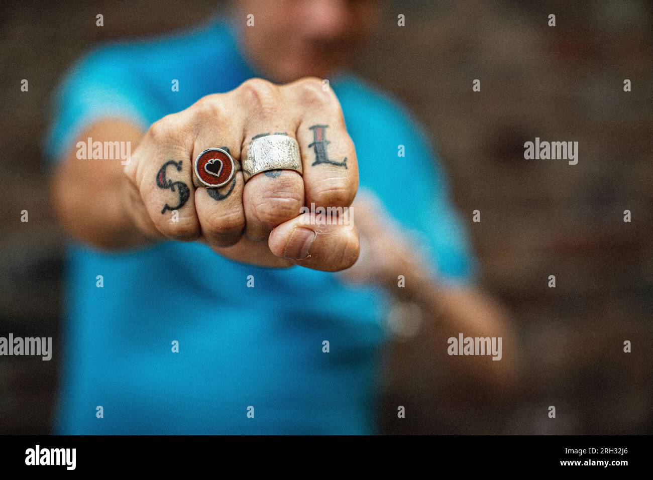 Uomo che si infilava il pugno nella macchina fotografica, indossava un grande anello con un tatuaggio dell'anima sulle dita a londra, regno unito Foto Stock
