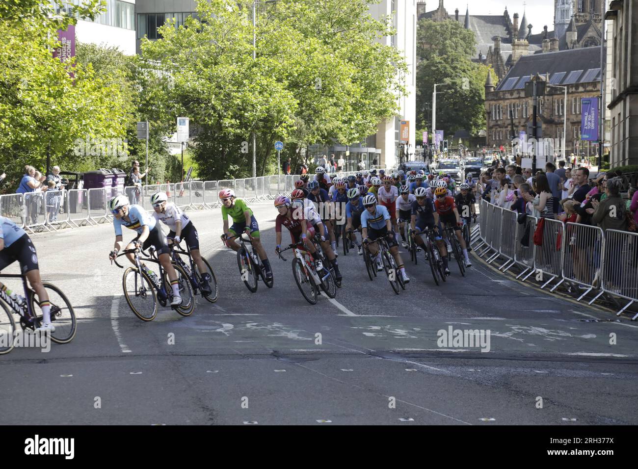 Glasgow, Scozia, Regno Unito. 13 agosto 2023. Gruppo ciclistico professionista internazionale nella fase dei giri della città della UCI Cycling World Championships Women Elite Road Race, che ha avuto inizio a Loch Lomond e si è conclusa con sei giri di strade cittadine di Glasgow. I ciclisti si stanno trasformando da University Avenue in Byres Road nel West End della città. Crediti: Elizabeth Leyden/Alamy Live News Foto Stock