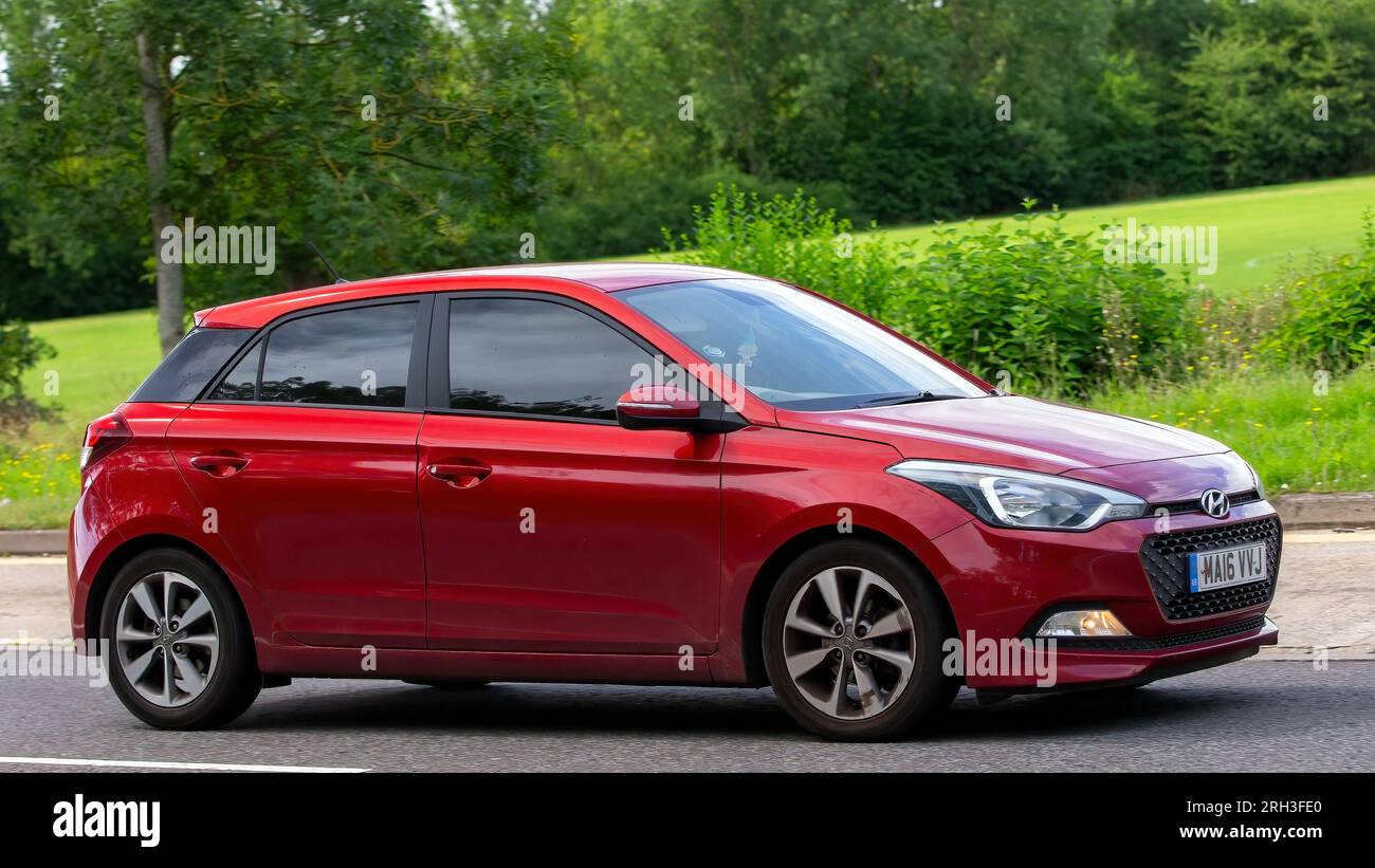 Milton Keynes, Regno Unito - 13 agosto 2023:2016 auto rossa Hyundai i20 che guida su una strada di campagna inglese. Foto Stock
