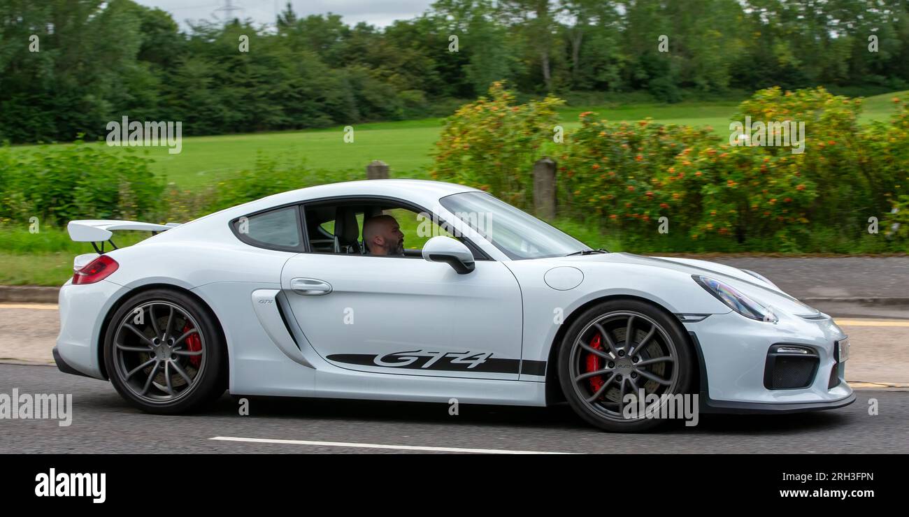 Milton Keynes, Regno Unito - 10 agosto 2023: 2016 auto Porsche Cayman GT4 bianca che guida su una strada di campagna inglese. Foto Stock