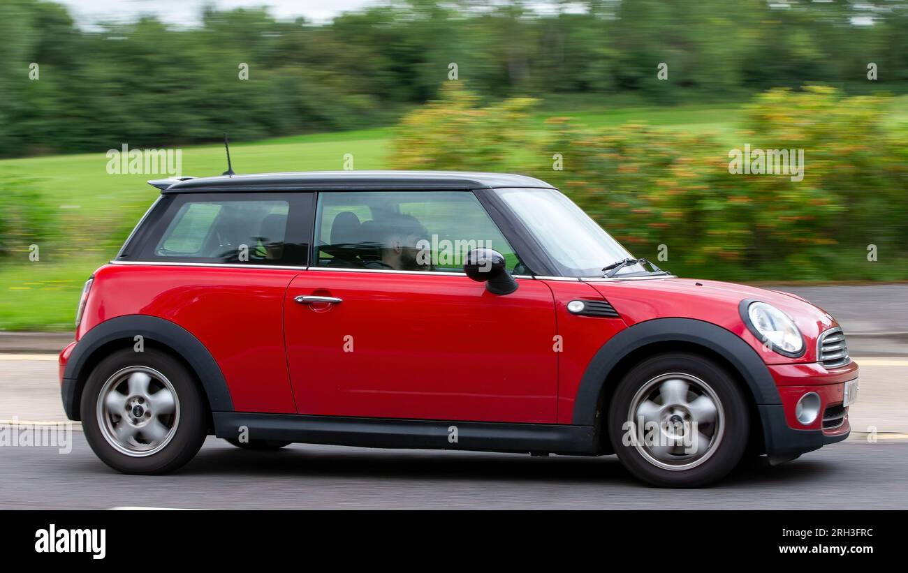 Milton Keynes, Regno Unito - 13 agosto 2023: 2010 Mini car rossa che guida su una strada di campagna inglese. Foto Stock