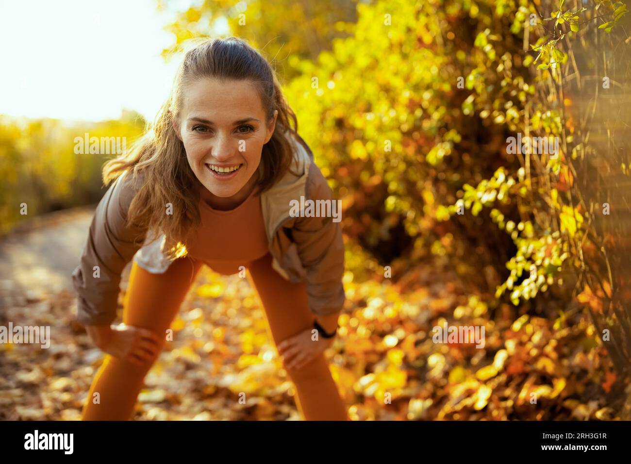 Ciao autunno. donna elegante sorridente in abiti fitness nel parco che si allunga. Foto Stock