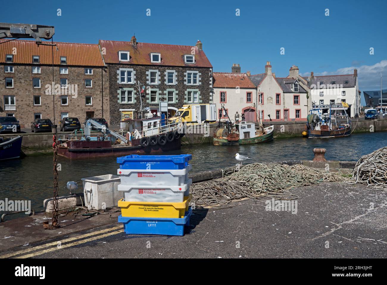 Scatole di pesce e corda sul molo in un tranquillo Eyemouth Harbour a Berwickshire, Scozia, Regno Unito. Foto Stock