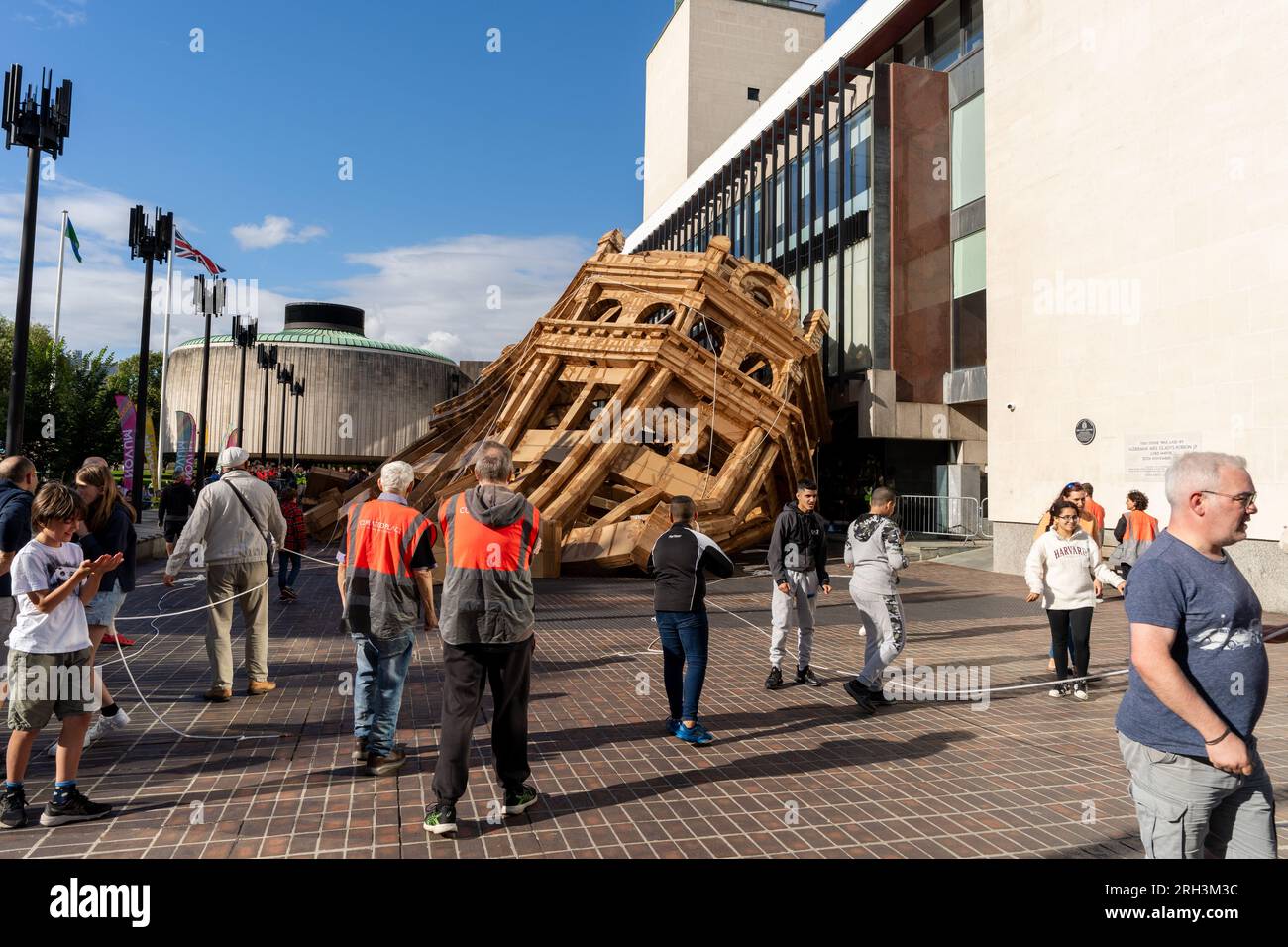 Newcastle upon Tyne, Regno Unito. 13 agosto 2023. Novum Summer Festival - demolizione della "costruzione monumentale" - un edificio in cartone di 45 piedi (14 metri) creato dall'artista visuale francese Olivier Grossetête e da volontari, e poi decostruito. Novum è un nuovissimo festival multi-arte che mette in mostra talenti locali, nazionali e internazionali presso il Centro Civico della città. -- l'edificio è tirato a terra. Crediti: Hazel Plater/Alamy Live News Foto Stock