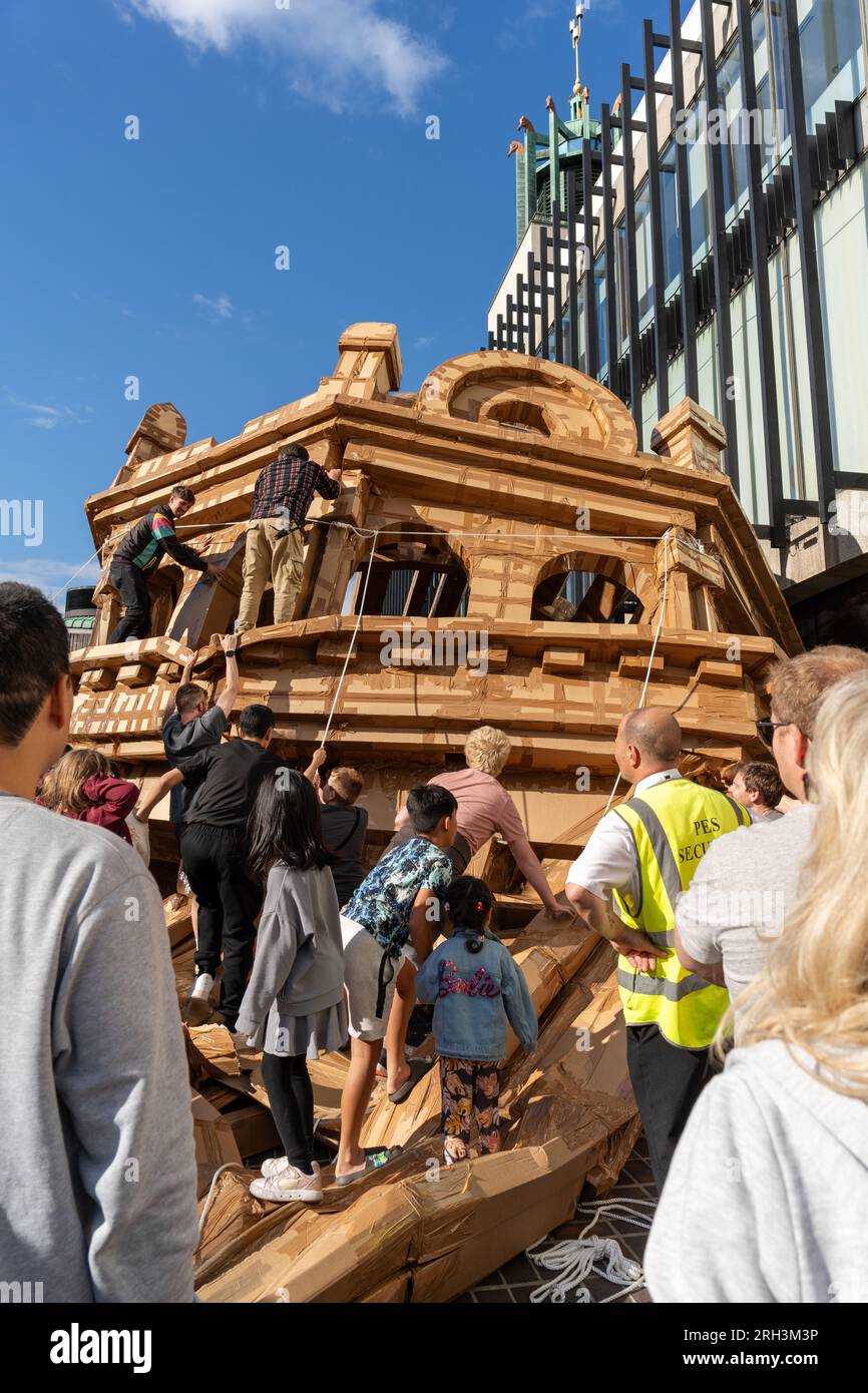 Newcastle upon Tyne, Regno Unito. 13 agosto 2023. Novum Summer Festival - demolizione della "costruzione monumentale" - un edificio in cartone di 45 piedi (14 metri) creato dall'artista visuale francese Olivier Grossetête e da volontari, e poi decostruito. Novum è un nuovissimo festival multi-arte che mette in mostra talenti locali, nazionali e internazionali presso il Centro Civico della città. -- l'edificio è distrutto dal pubblico. Crediti: Hazel Plater/Alamy Live News Foto Stock