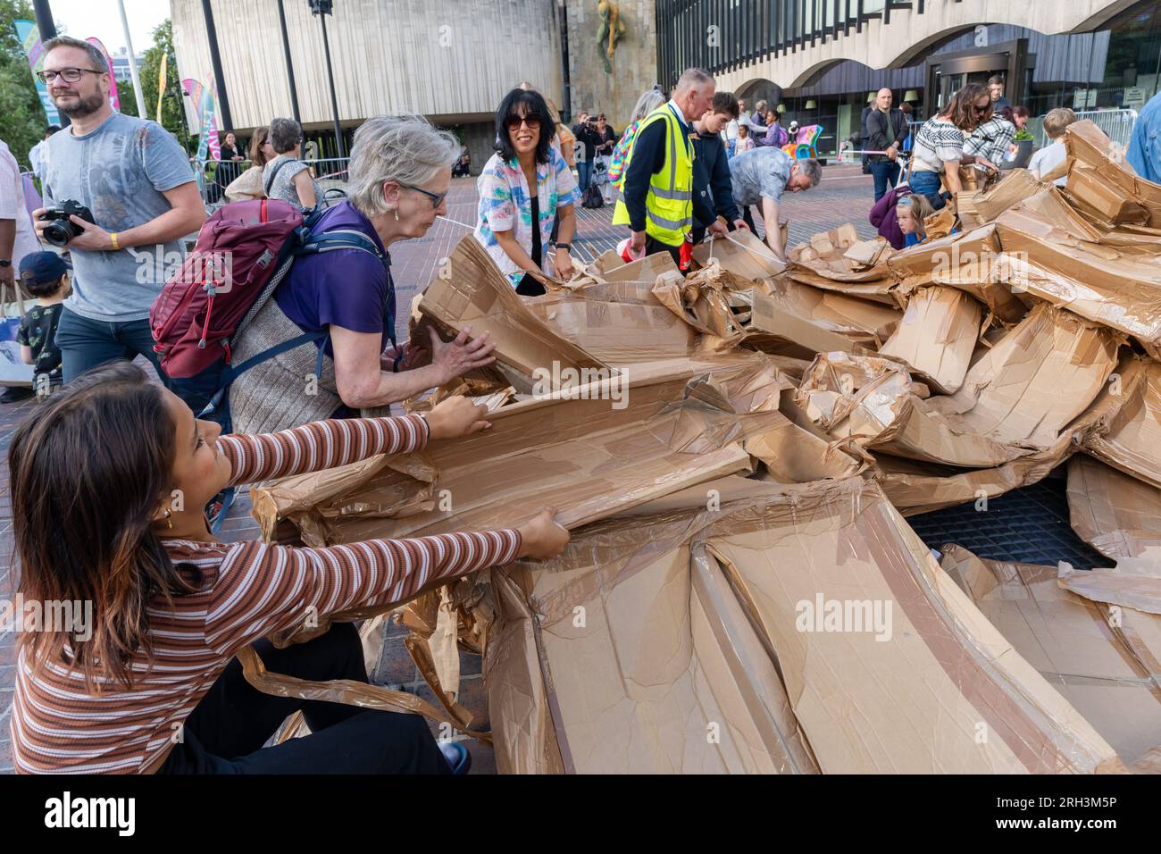 Newcastle upon Tyne, Regno Unito. 13 agosto 2023. Novum Summer Festival - demolizione della "costruzione monumentale" - un edificio in cartone di 45 piedi (14 metri) creato dall'artista visuale francese Olivier Grossetête e da volontari, e poi decostruito. Novum è un nuovissimo festival multi-arte che mette in mostra talenti locali, nazionali e internazionali presso il Centro Civico della città. -- l'edificio è smembrato dal pubblico. Crediti: Hazel Plater/Alamy Live News Foto Stock