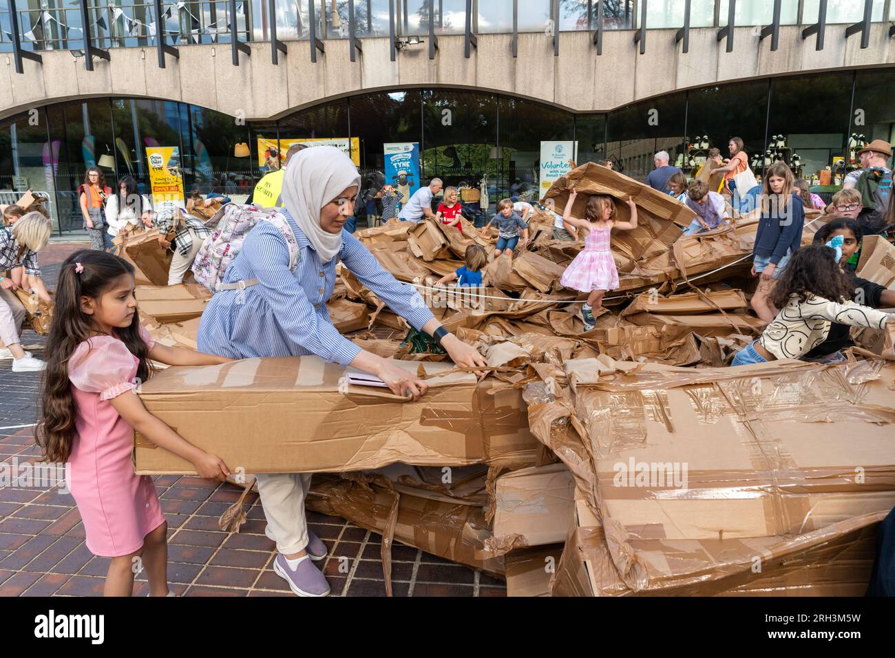 Newcastle upon Tyne, Regno Unito. 13 agosto 2023. Novum Summer Festival - demolizione della "costruzione monumentale" - un edificio in cartone di 45 piedi (14 metri) creato dall'artista visuale francese Olivier Grossetête e da volontari, e poi decostruito. Novum è un nuovissimo festival multi-arte che mette in mostra talenti locali, nazionali e internazionali presso il Centro Civico della città. -- l'edificio è smembrato dal pubblico. Crediti: Hazel Plater/Alamy Live News Foto Stock