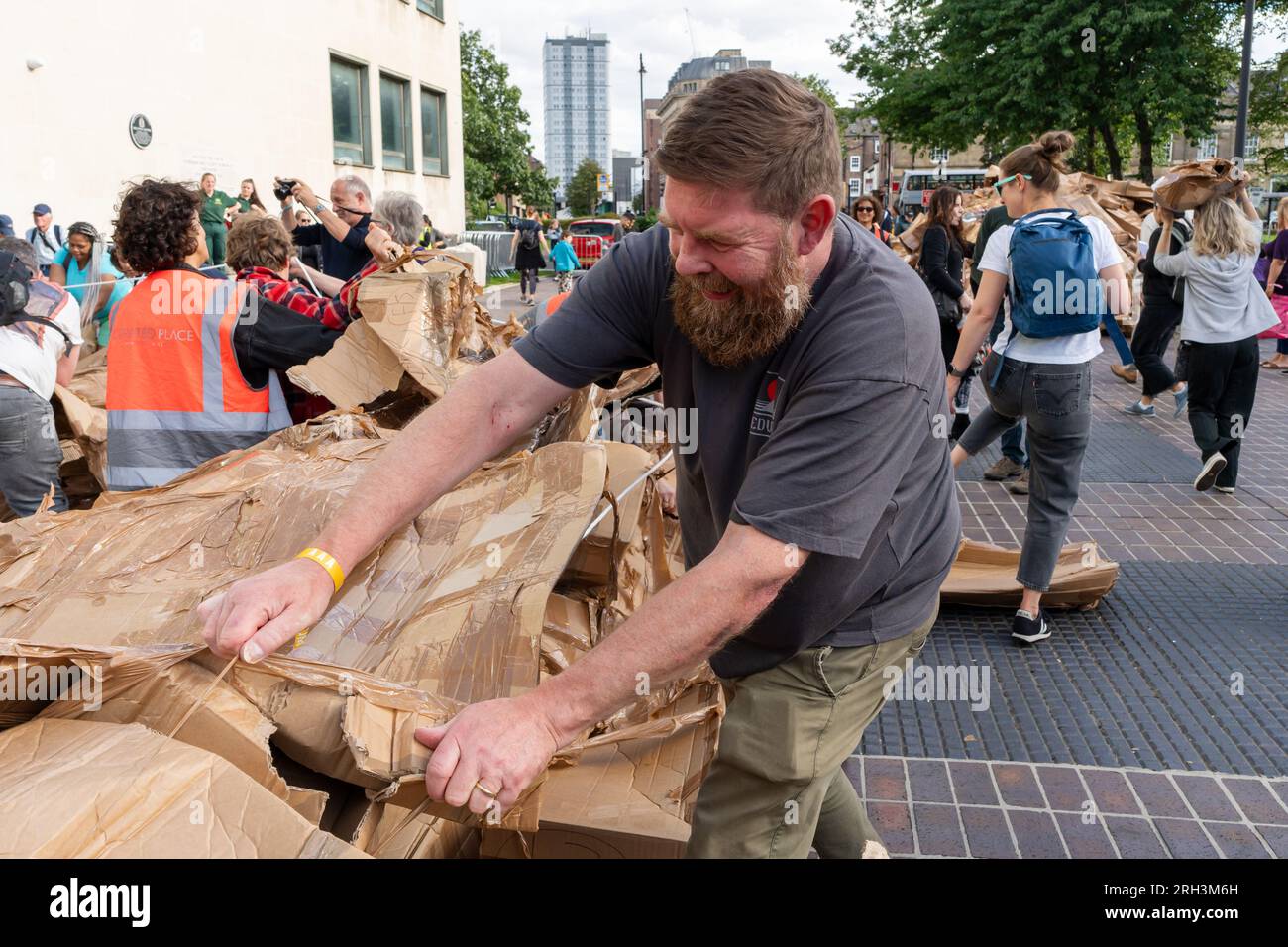 Newcastle upon Tyne, Regno Unito. 13 agosto 2023. Novum Summer Festival - demolizione della "costruzione monumentale" - un edificio in cartone di 45 piedi (14 metri) creato dall'artista visuale francese Olivier Grossetête e da volontari, e poi decostruito. Novum è un nuovissimo festival multi-arte che mette in mostra talenti locali, nazionali e internazionali presso il Centro Civico della città. Jim Mawsdley, consigliere principale eventi e cultura del Consiglio cittadino di Newcastle aiuta con la demolizione. Crediti: Hazel Plater/Alamy Live News Foto Stock