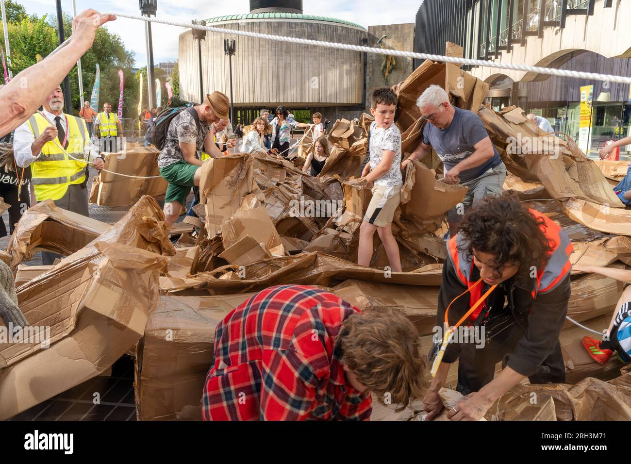 Newcastle upon Tyne, Regno Unito. 13 agosto 2023. Novum Summer Festival - demolizione della "costruzione monumentale" - un edificio in cartone di 45 piedi (14 metri) creato dall'artista visuale francese Olivier Grossetête e da volontari, e poi decostruito. Novum è un nuovissimo festival multi-arte che mette in mostra talenti locali, nazionali e internazionali presso il Centro Civico della città. -- l'edificio è smembrato dal pubblico. Crediti: Hazel Plater/Alamy Live News Foto Stock