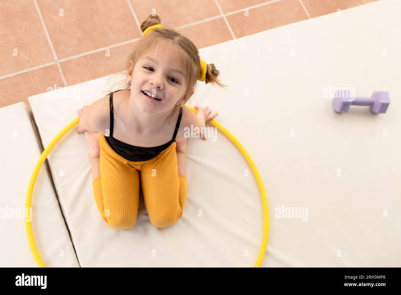 Piccola ragazza bionda con code piggy che gioca con hula hoop Foto Stock