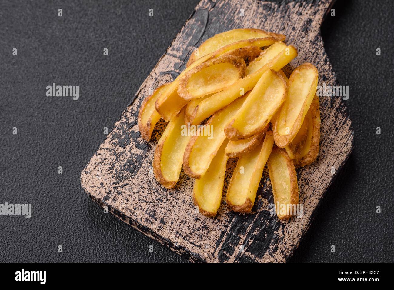 Deliziose patate croccanti con sale e spezie su uno sfondo in cemento ruvido. Fast food Foto Stock