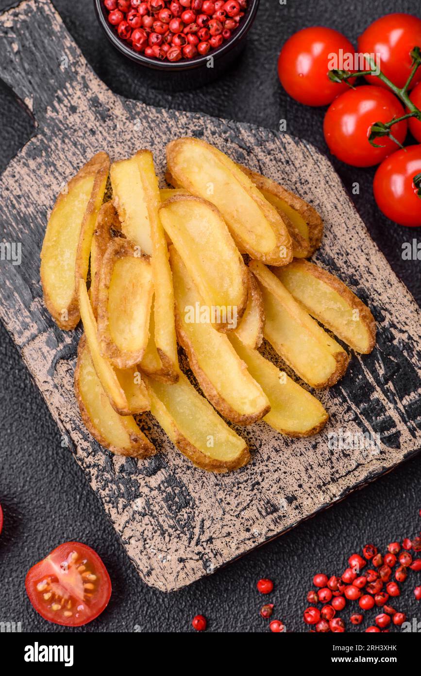 Deliziose patate croccanti con sale e spezie su uno sfondo in cemento ruvido. Fast food Foto Stock
