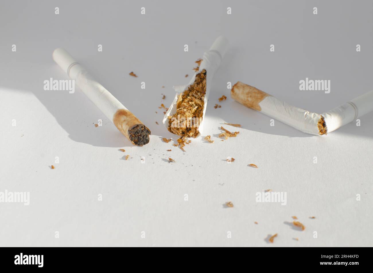 Dettaglio delle sigarette su una superficie bianca, che simboleggia i rischi per la salute e le malattie associate al fumo. Foto Stock
