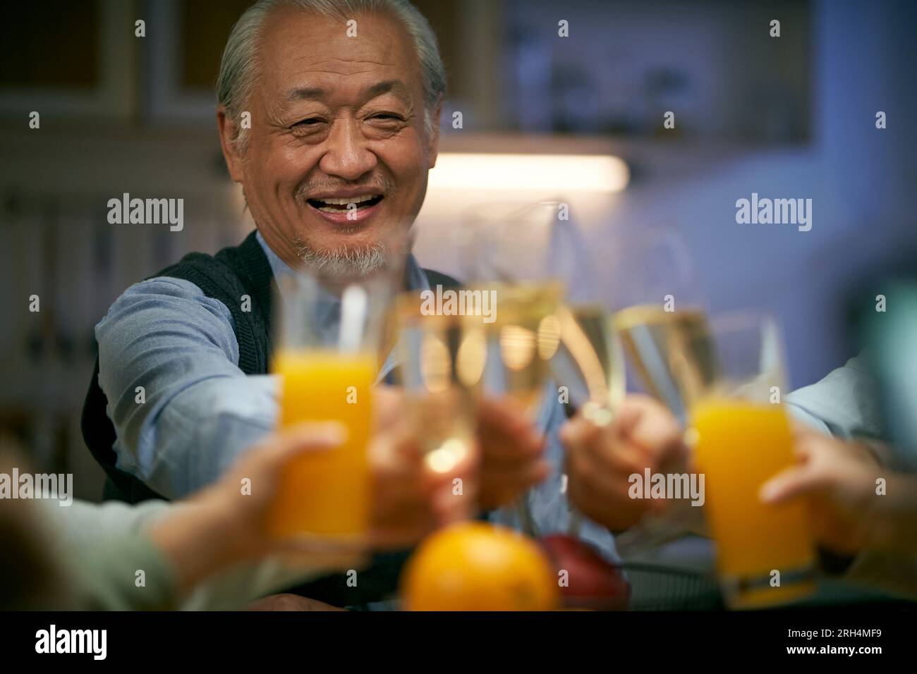 un anziano asiatico brindisi durante la riunione di famiglia felice e sorridente Foto Stock