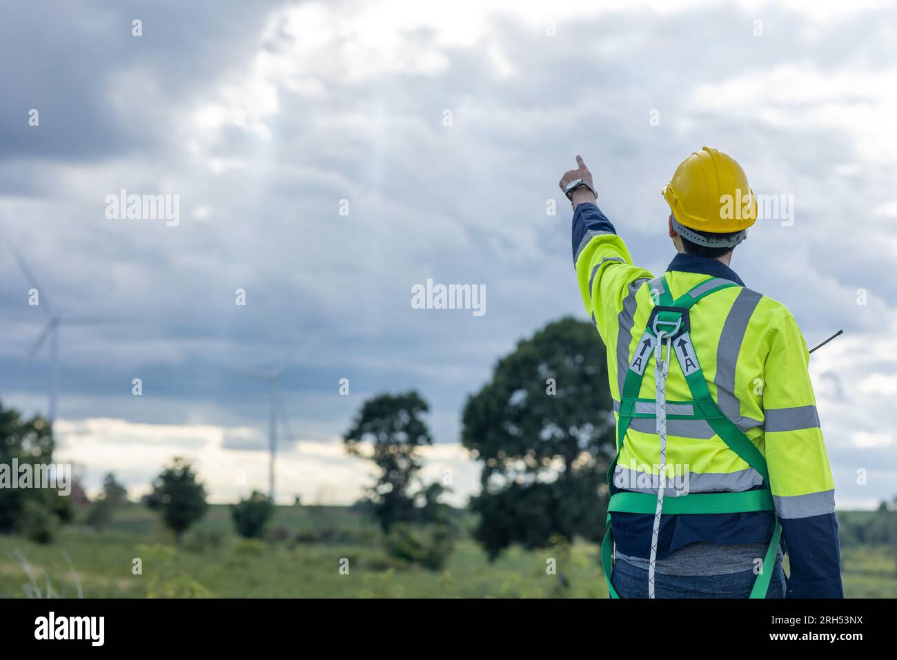 Ingegnere maschio che lavora in turbine eoliche, vista posteriore dell'azienda, puntando verso il cielo per il futuro dei lavoratori che lavorano nel settore dell'energia pulita Foto Stock