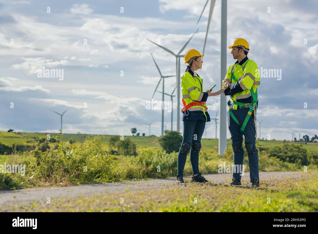 Team di ingegneri, uomo e donna, che lavorano sul campo, piano di indagine, costruzione di turbine eoliche, generatore di energia pulita Foto Stock