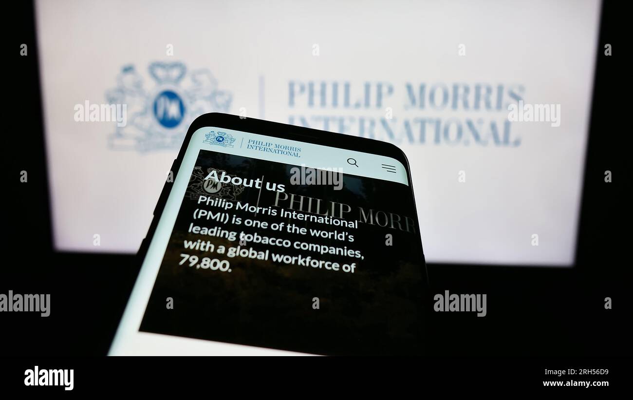 Telefono cellulare con sito Web dell'azienda statunitense Philip Morris International Inc. Sullo schermo davanti al logo aziendale. Mettere a fuoco in alto a sinistra sul display del telefono. Foto Stock