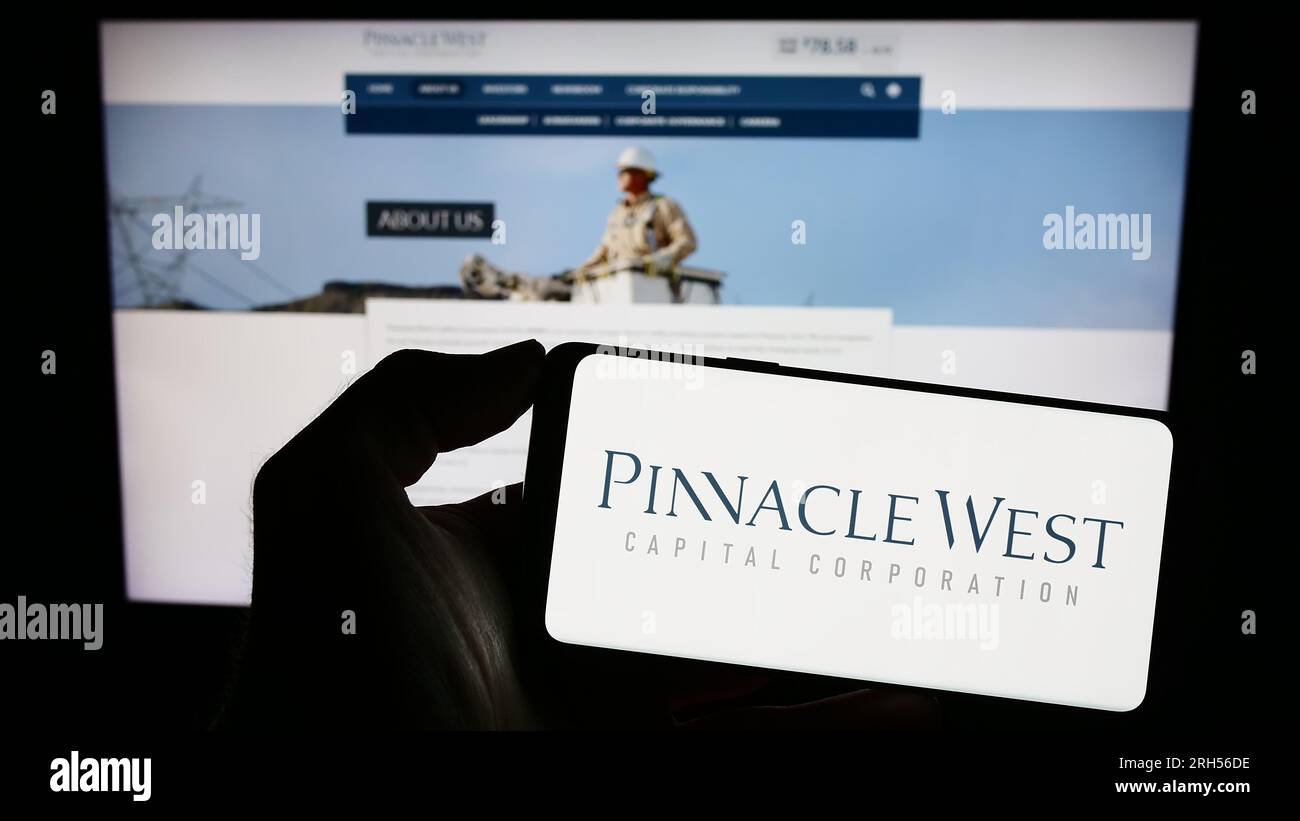 Persona che possiede uno smartphone con il logo della società statunitense Pinnacle West Capital Corporation sullo schermo di fronte al sito Web. Concentrarsi sul display del telefono. Foto Stock