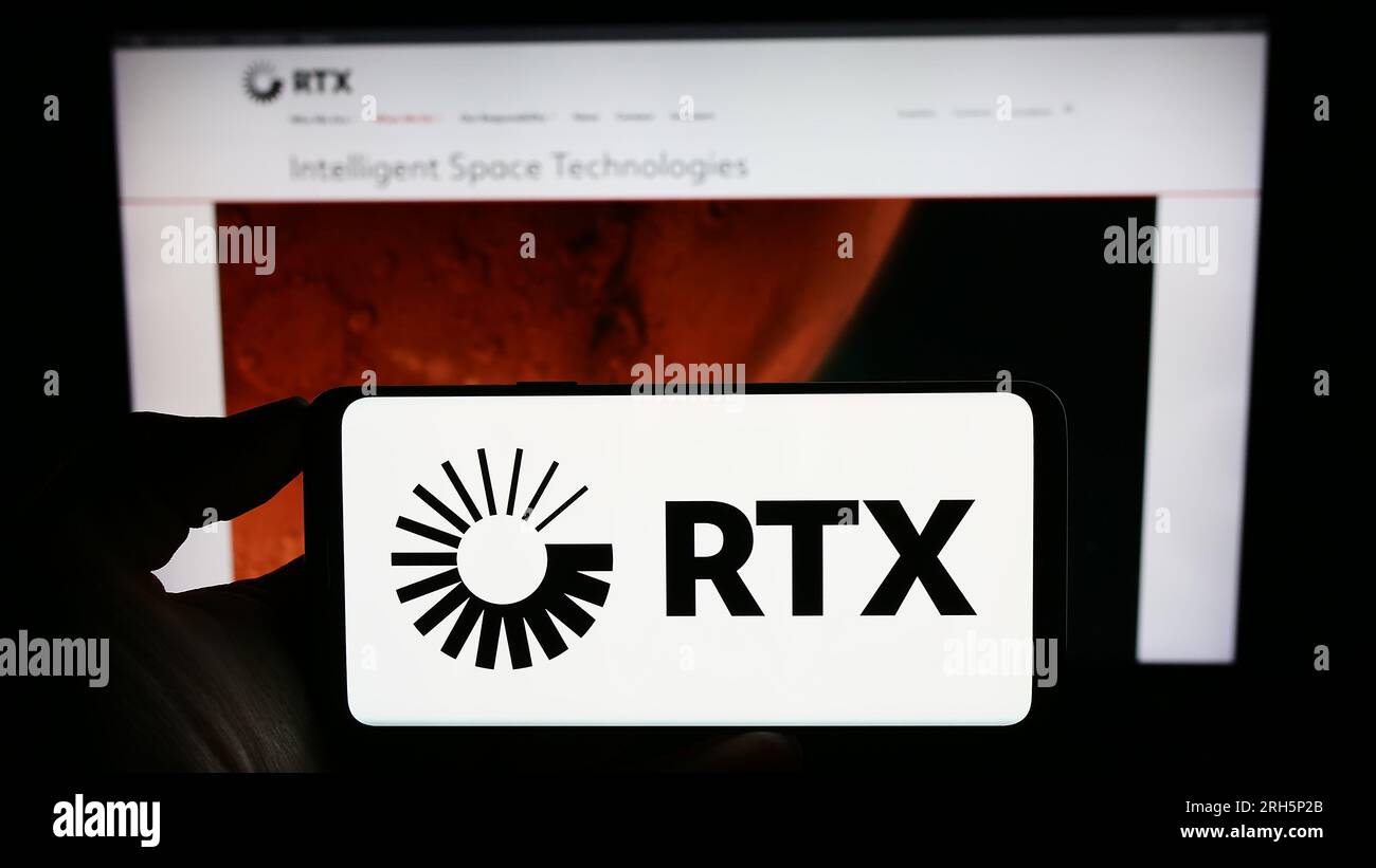 Persona che detiene il cellulare con il logo della società statunitense per il settore aerospaziale e della difesa RTX Corporation sullo schermo davanti alla pagina Web. Concentrarsi sul display del telefono. Foto Stock