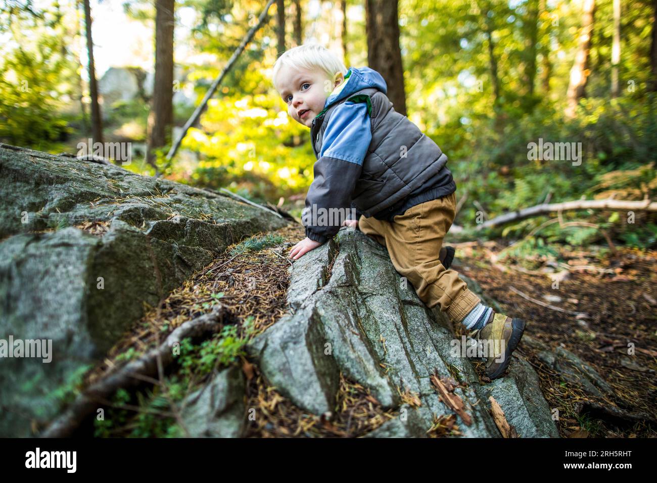 Giovane ragazzo arrampicata su rocce nella natura, spirito avventuroso Foto Stock