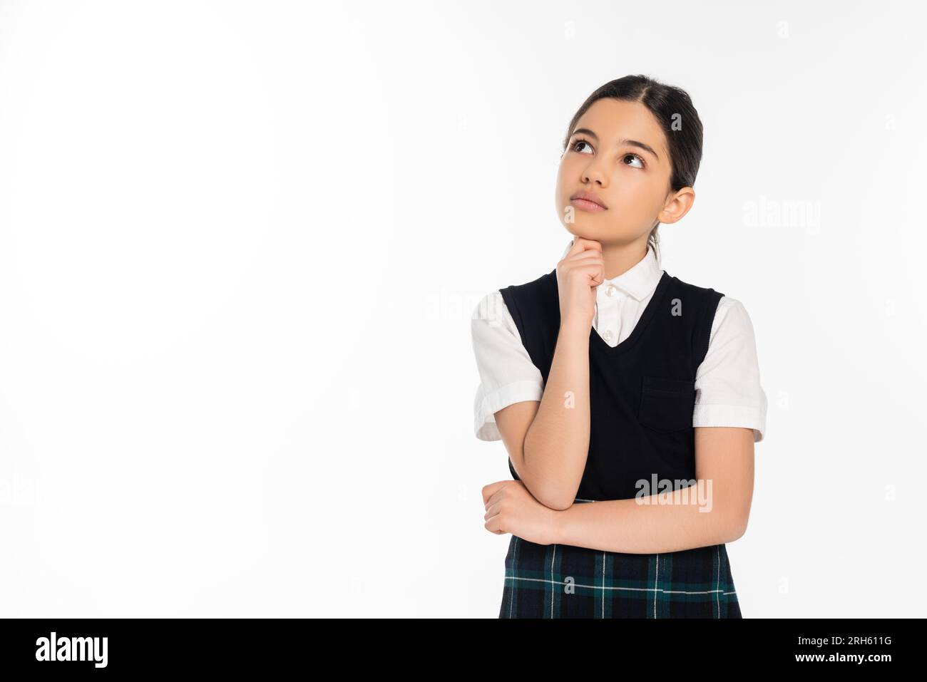 una studentessa pensiva in giubbotto nero che guarda lontano isolata sul bianco, pensante, uniforme scolastica, ragazzina Foto Stock