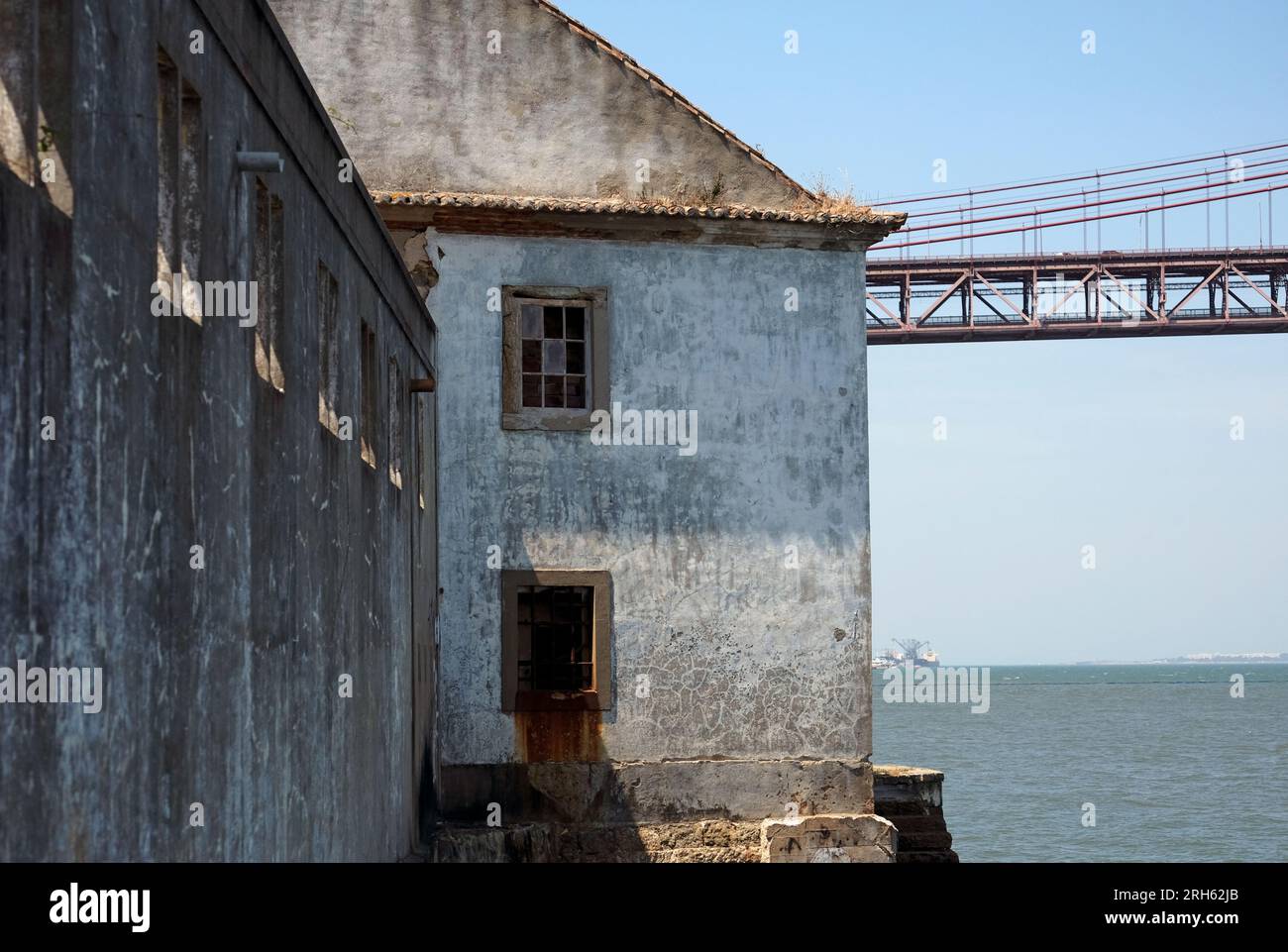 Il ponte "Ponte 25 de Abril" a Lisbona, Portogallo, con un edificio abbandonato in primo piano Foto Stock