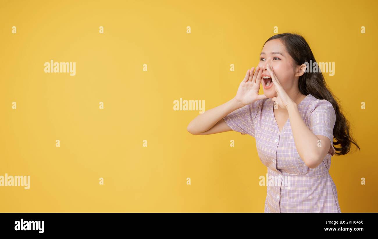 Donna teen in piedi grande grida con le mani bocca successiva dando positivo eccitato, presente e chiamata su sfondo arancione Foto Stock