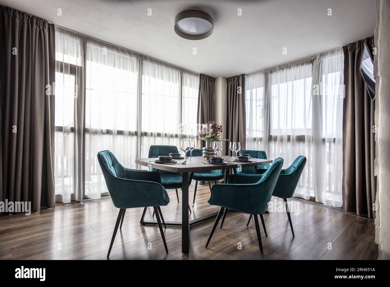 Sala da pranzo con tavolo in legno e pavimento con sedie blu in un appartamento moderno. Foto Stock