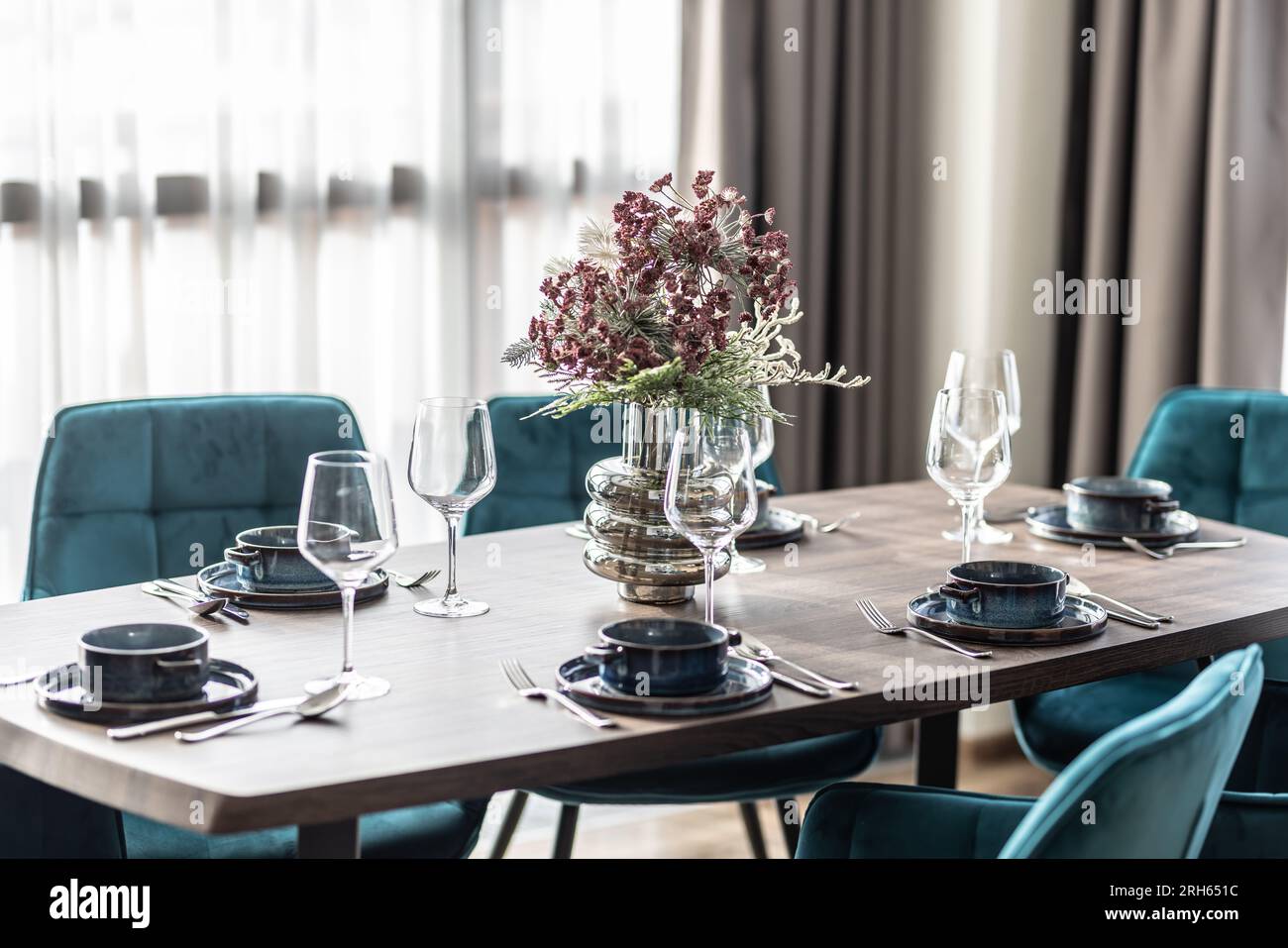 Sala da pranzo con tavolo in legno e pavimento con sedie blu in un appartamento moderno. Ambiente moderno nella zona pranzo dell'appartamento. Foto Stock