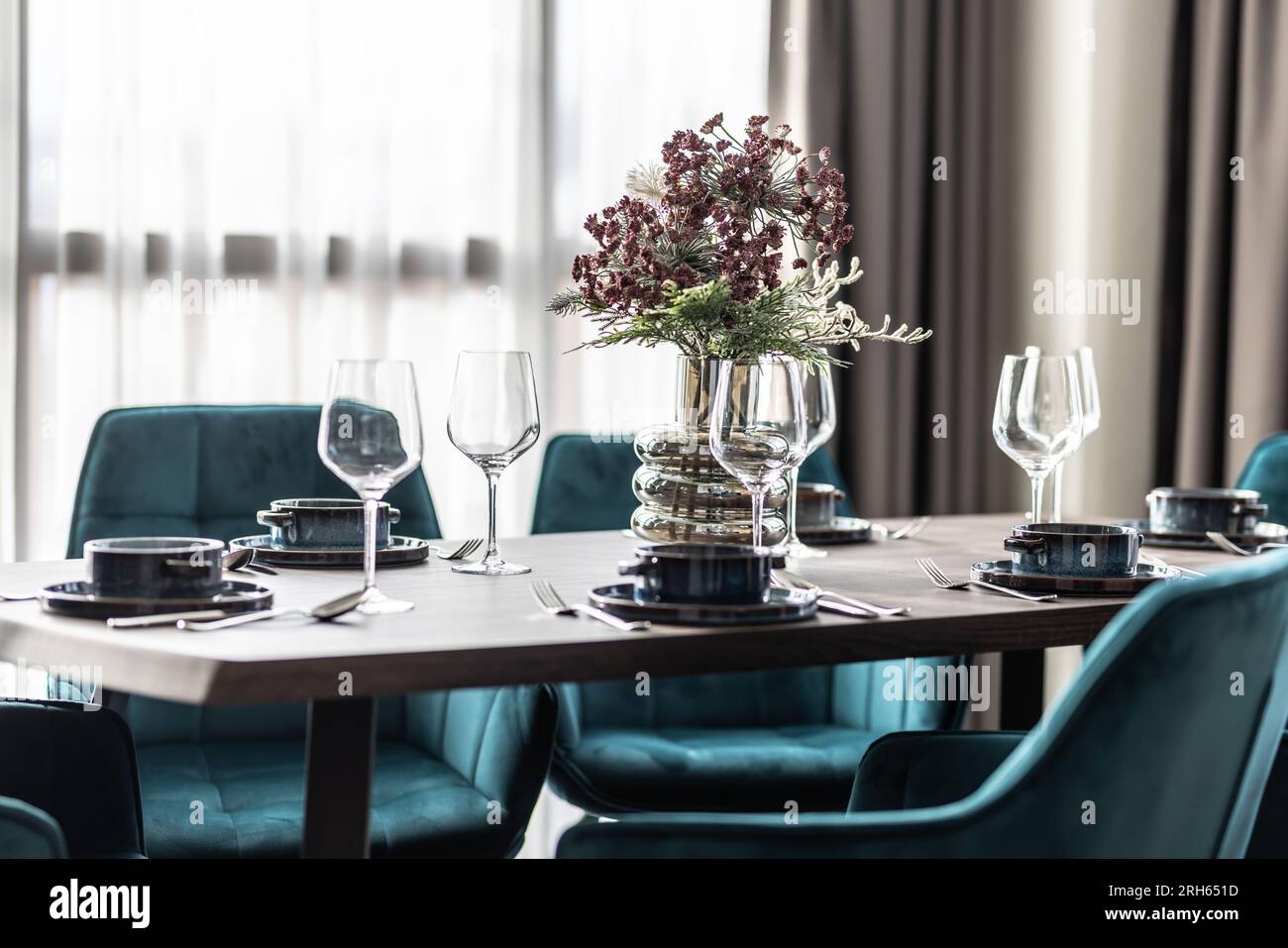 Sala da pranzo con tavolo in legno e pavimento con sedie blu in un appartamento moderno. Ambiente moderno nella zona pranzo dell'appartamento. Foto Stock