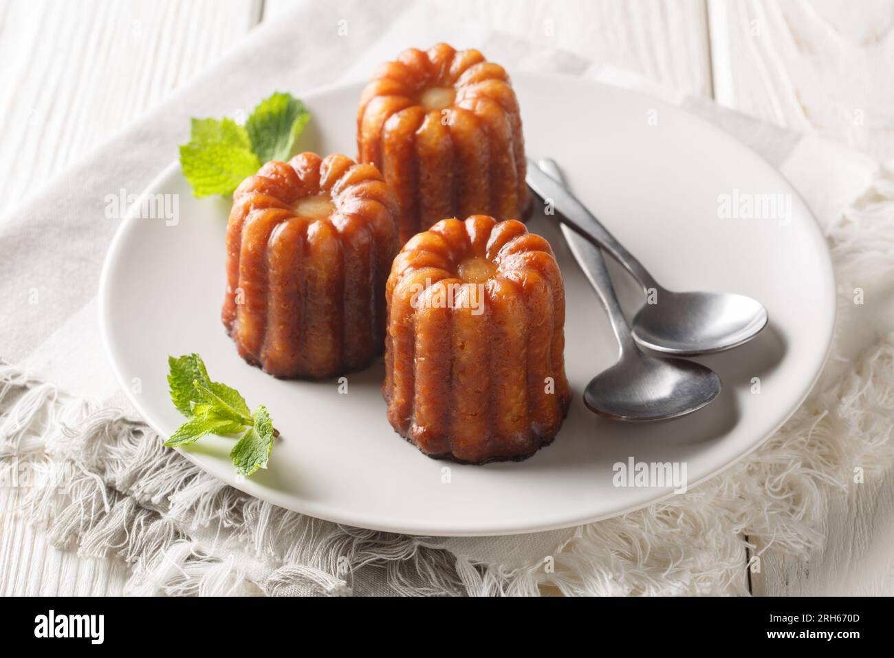 Canele è una piccola pasticceria francese con rum e vaniglia da vicino in un piatto sul tavolo. Orizzontale Foto Stock