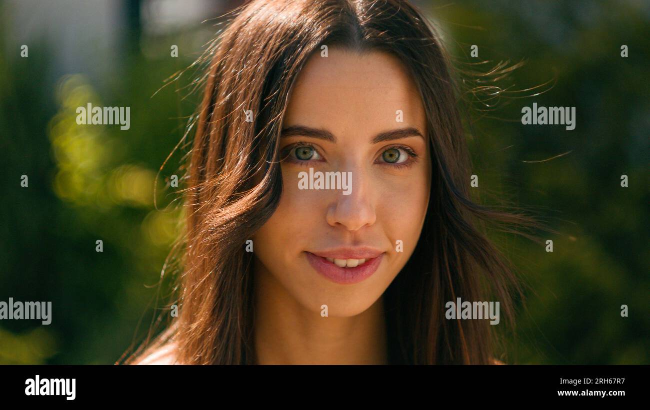 Primo piano sorridente felice attraente donna ispanica che guarda lo stand della macchina fotografica nel parco cittadino in strada, estate, giorno di sole, bella e sicura araba Foto Stock