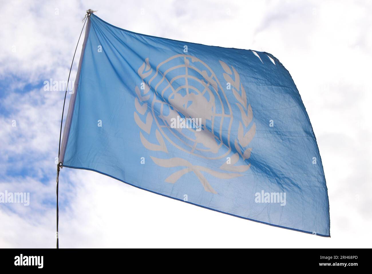 Bandiera ONU retroilluminata che sventola nel vento. Emblema ufficiale delle Nazioni Unite. Concetto di pace nel mondo Foto Stock