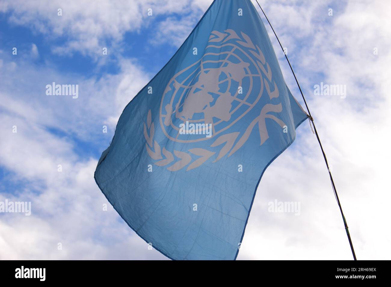 Bandiera ONU retroilluminata che sventola nel vento. Emblema ufficiale delle Nazioni Unite. Concetto di pace nel mondo Foto Stock