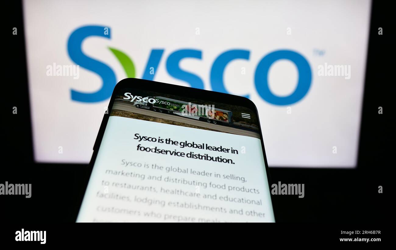 Smartphone con pagina Web della società all'ingrosso statunitense Sysco Corporation sullo schermo davanti al logo aziendale. Mettere a fuoco in alto a sinistra sul display del telefono. Foto Stock