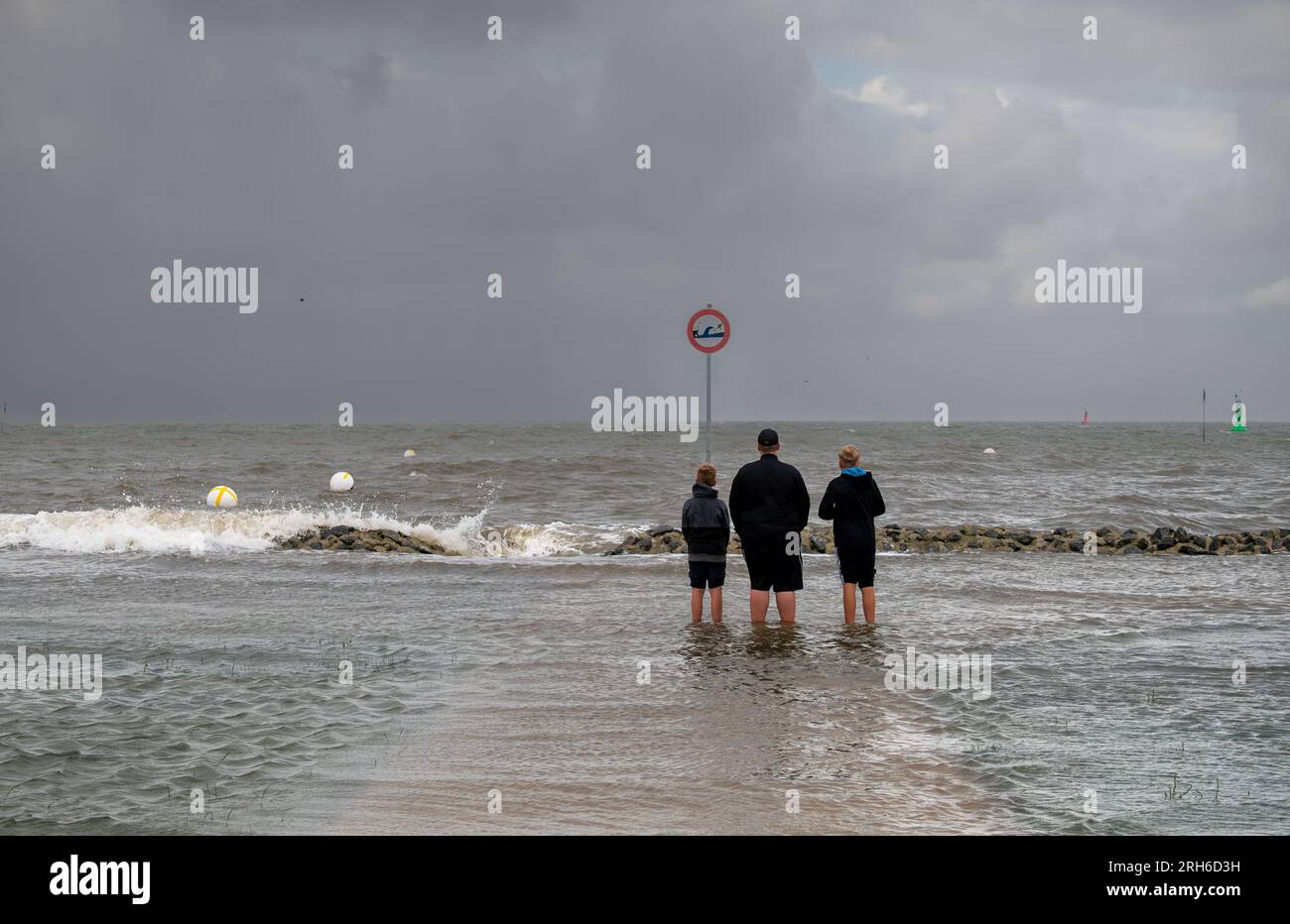 Famiglia in piedi in acqua durante un'inondazione di tempesta a Cuxhaven, Germania. Foto Stock