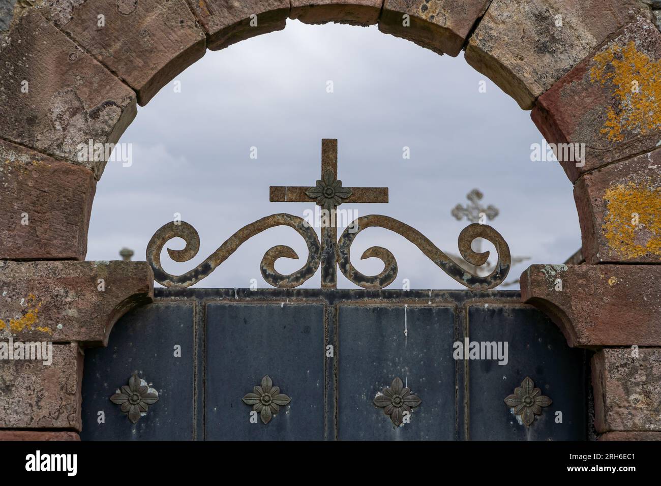 Misterioso cancello metallico del cimitero con croce e incroci lo sfondo Foto Stock