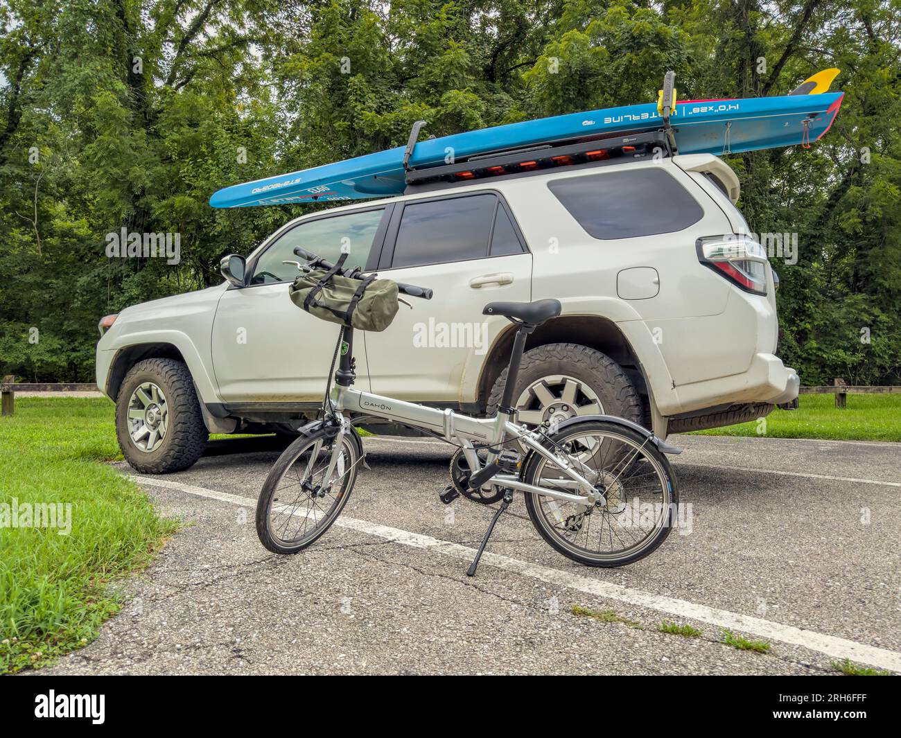 Rocheport, Missouri, USA - 3 agosto 2023: Bici pieghevole Dahon Mariner e SUV Toyota 4Runner con pedana in piedi sui portapacchi in un parcheggio di Katy Foto Stock