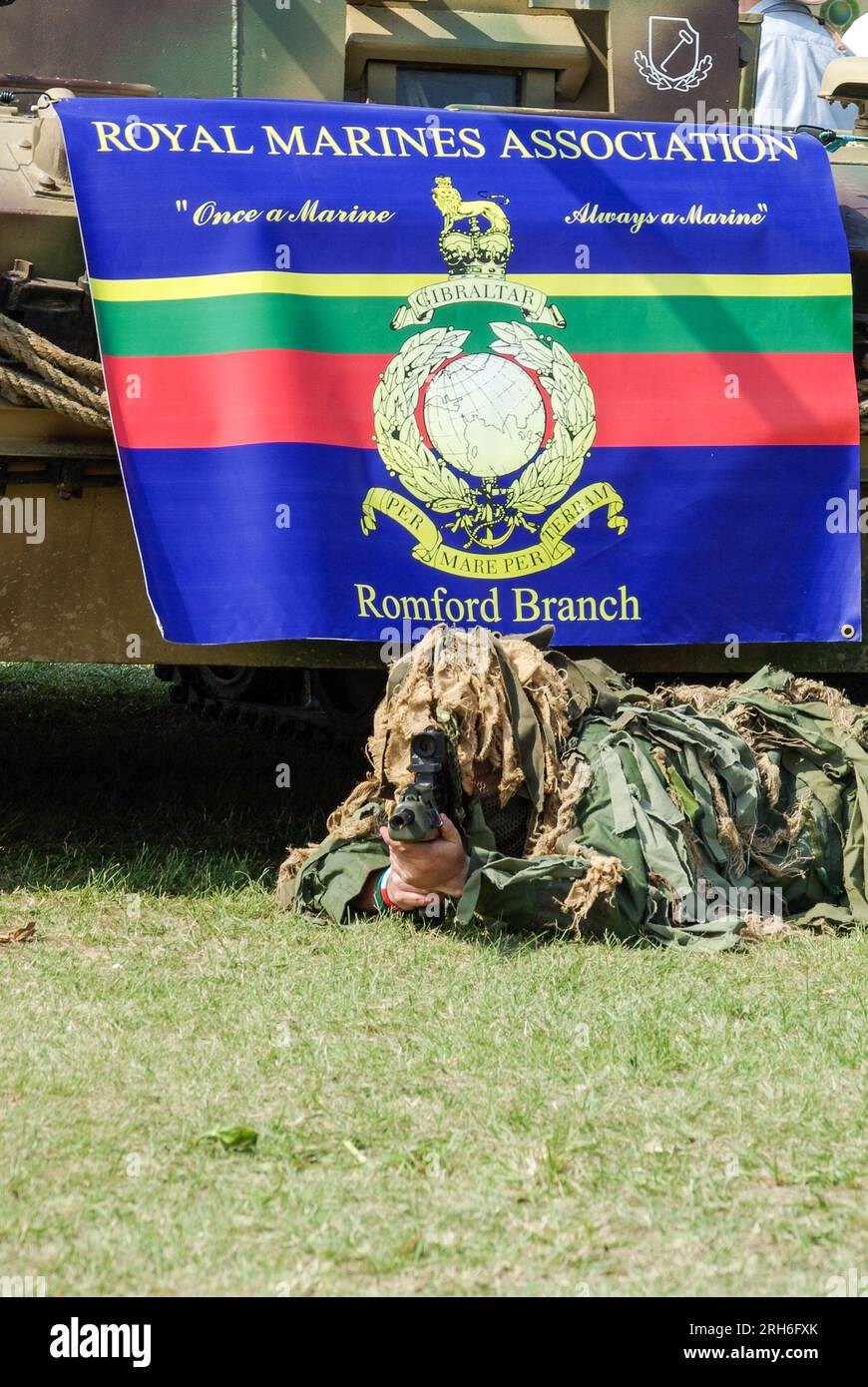 Royal Marines Association, Romford Branch, striscione all'evento militare Damyns Hall, Essex, Regno Unito, con soldato completamente camuffato che mira la pistola alla telecamera Foto Stock