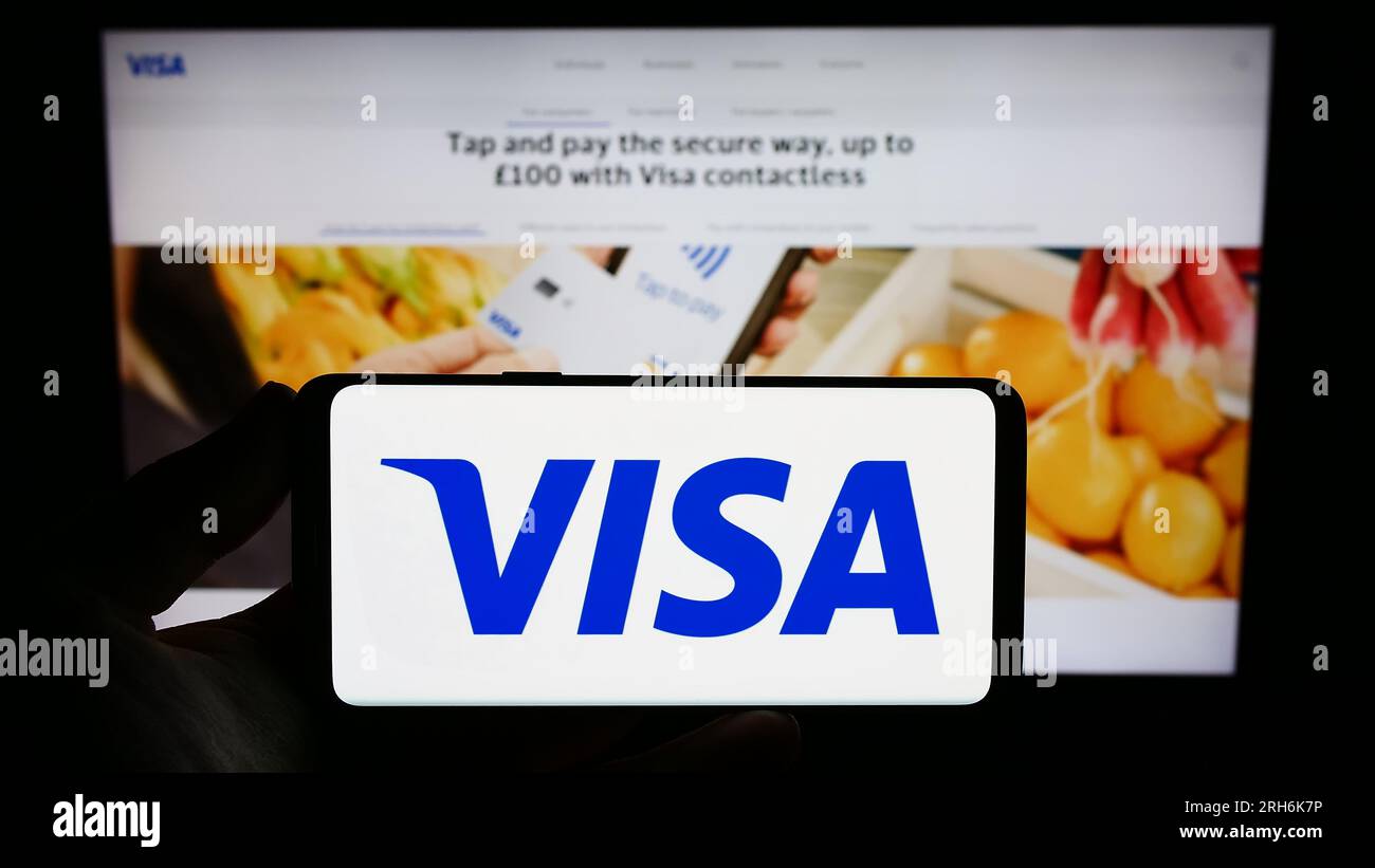 Persona che possiede uno smartphone con il logo della società statunitense di elaborazione dei pagamenti Visa Inc. Sullo schermo di fronte al sito Web. Concentrarsi sul display del telefono. Foto Stock