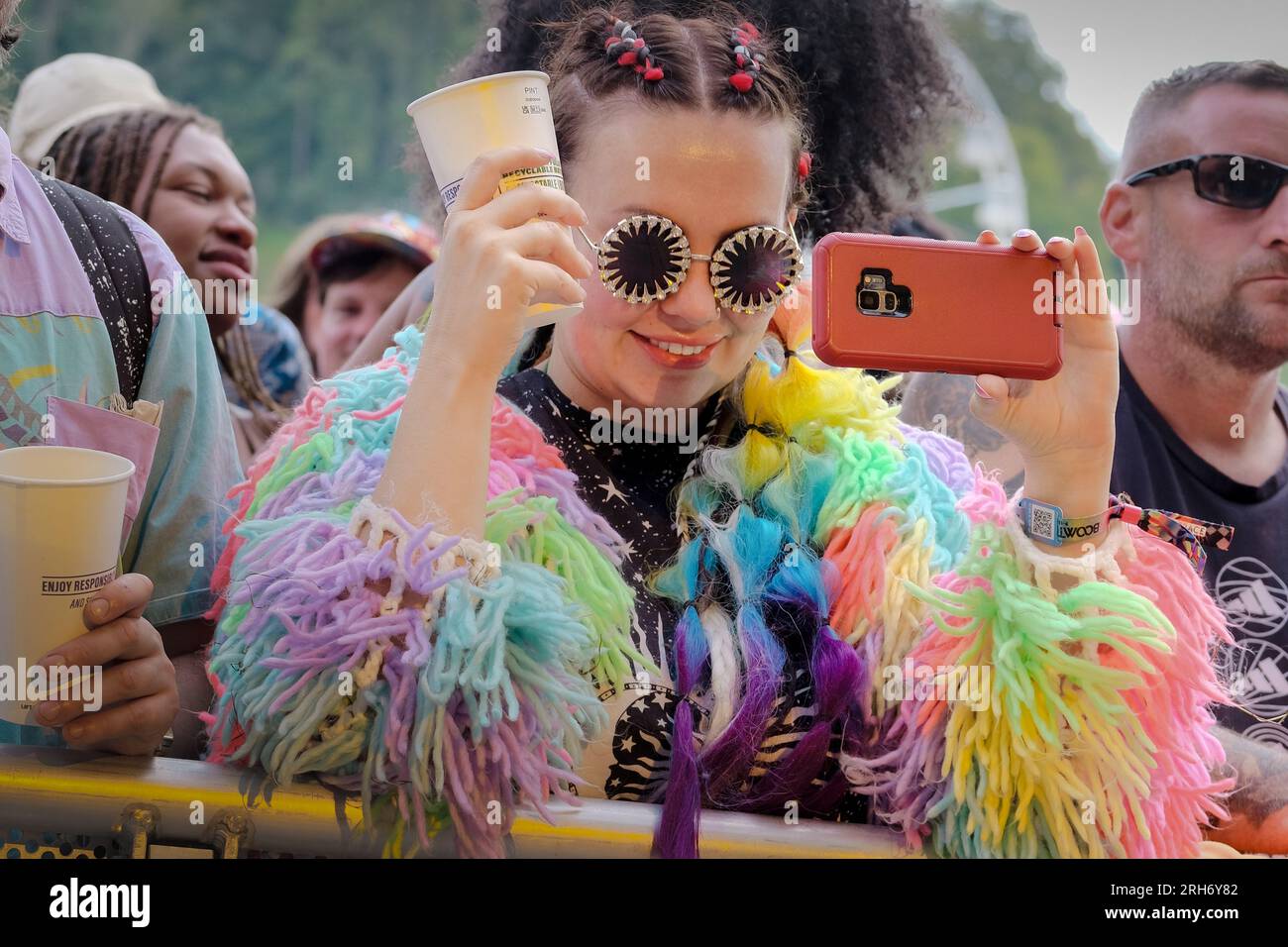 Una giovane donna che filma sul palco, indossa un cardigan multicolore