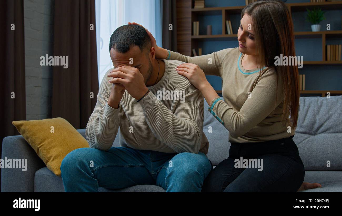 Disperato uomo triste sedersi sul divano sconvolto con cattive notizie lamentare la vita problema cura moglie sostegno ragazzo. Scusante donna dire scusa abbracciare infastidito Foto Stock